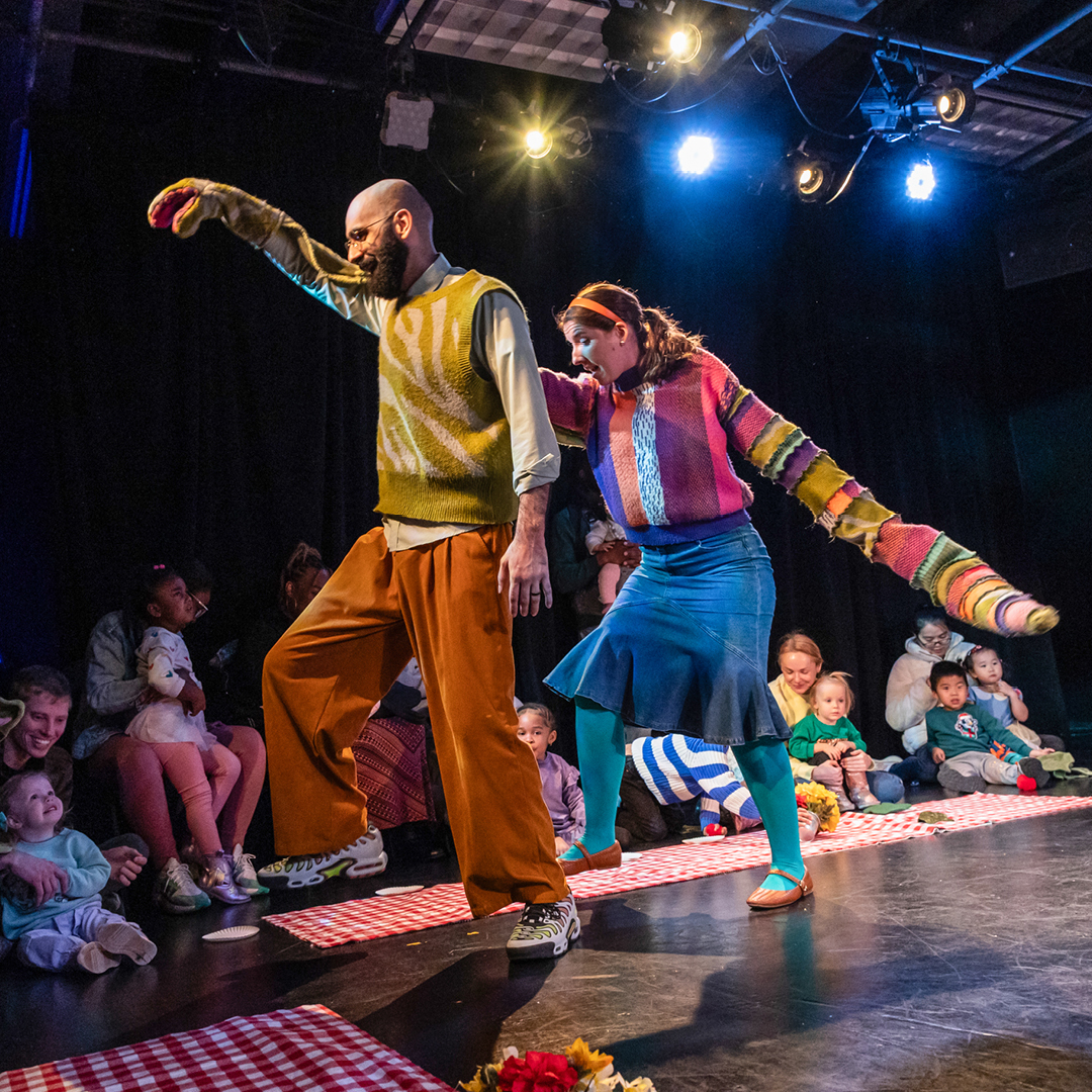 Two actors in Dinosaur! performing a scene for an audience of small children and parents.