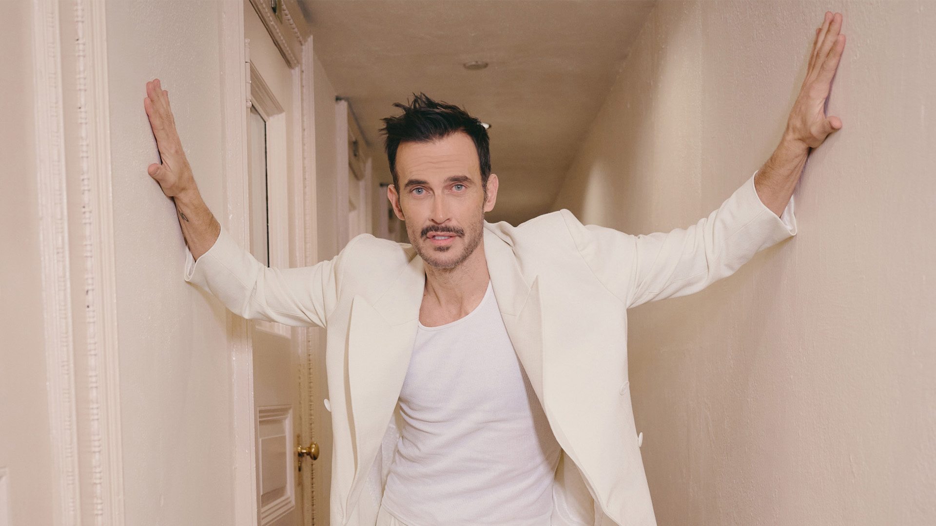 Cheyenne Jackson posing in a hallway.
