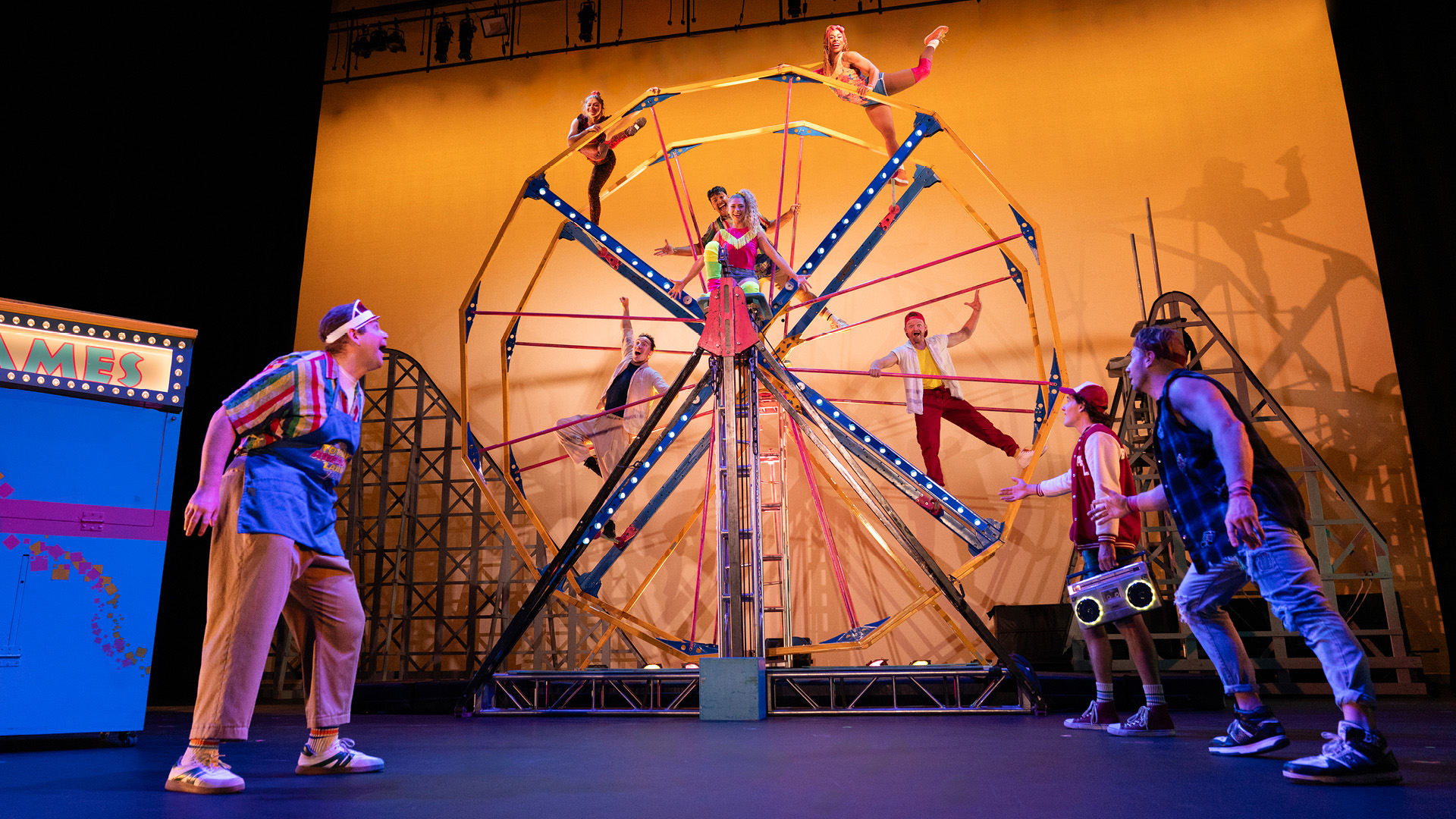 Cirque Mechanics acrobats perform in front of amusement park background.