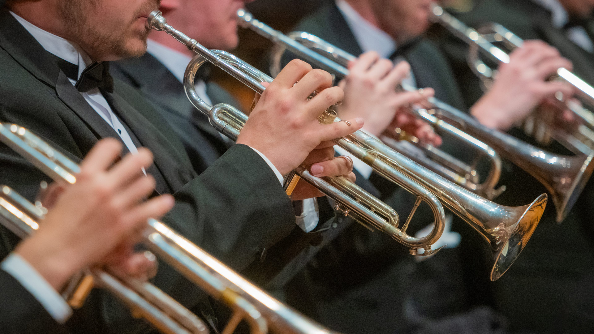 A row of seated trumpeters dressed in formal attire
